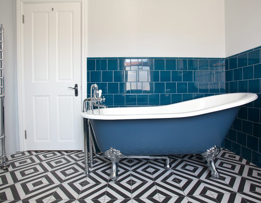 Image: Blue-tiled main bathroom with slipper bath and geometric flooring