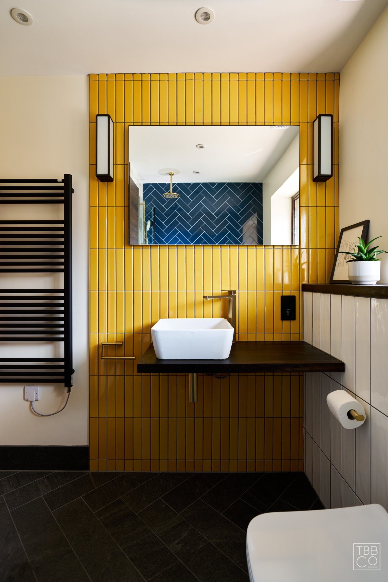 Yellow Feature Tiles with Black Wall Lights above Basin